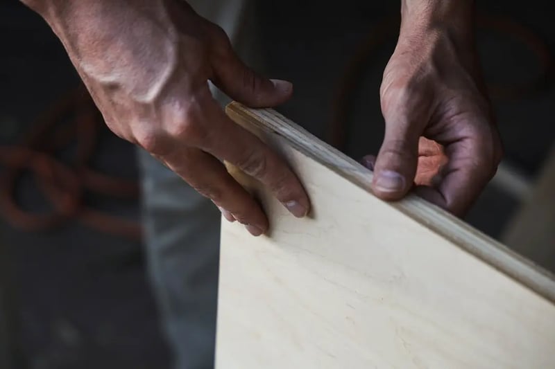 A thoughtful carpenter looking at a piece of wood, planning the next cut.