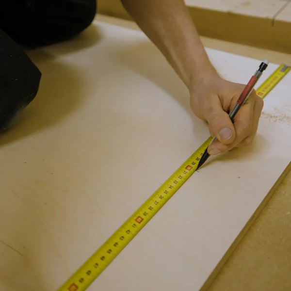 A tape measure lying on a wooden board, ready for measurement.